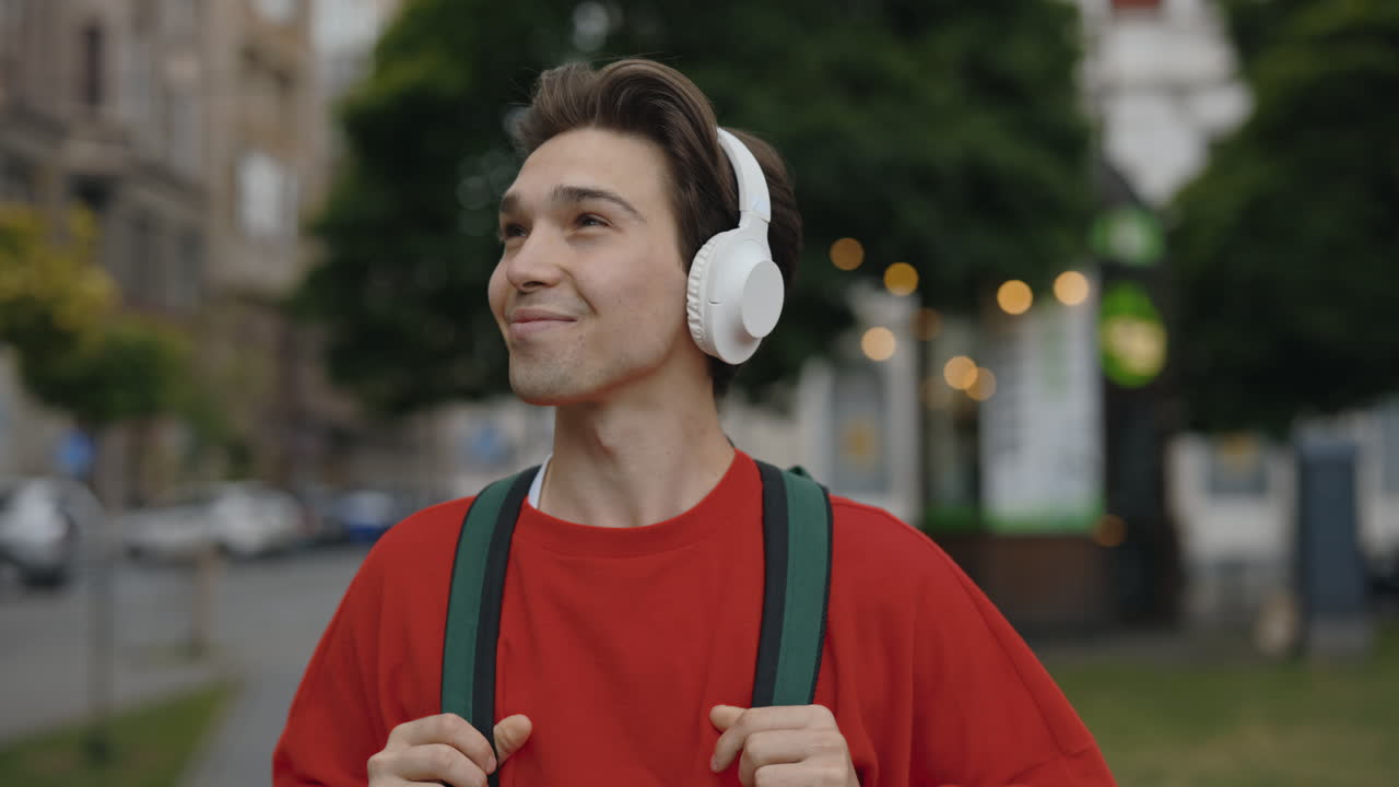 Giovane uomo con cuffie e zaino all'aperto
