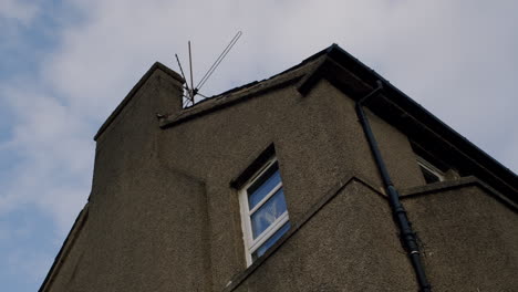 low angle view of building exterior with chimney on the side and old television antenna on the roof