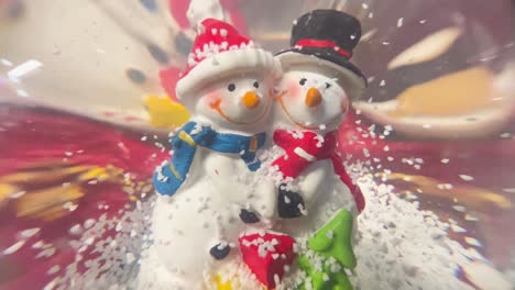 Two cheerful snowmen in a festive snow globe