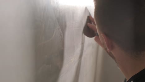 man plastering the walls with finishing putty in room with putty spatula