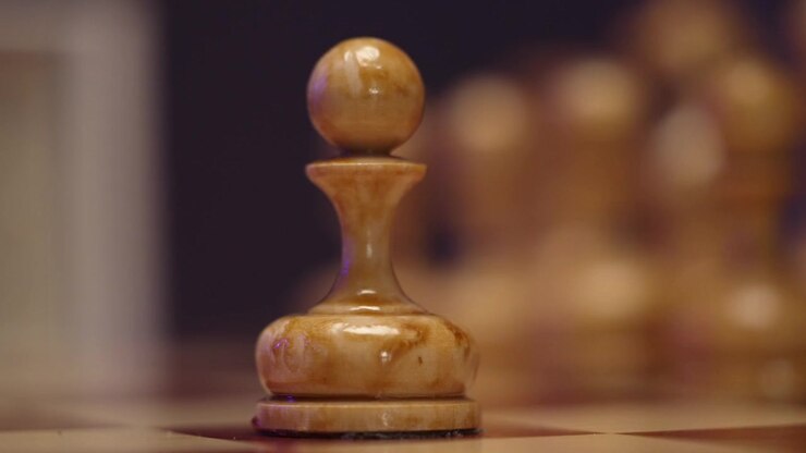 Close-up of Hand Placing a Wooden Pawn on a Chessboard