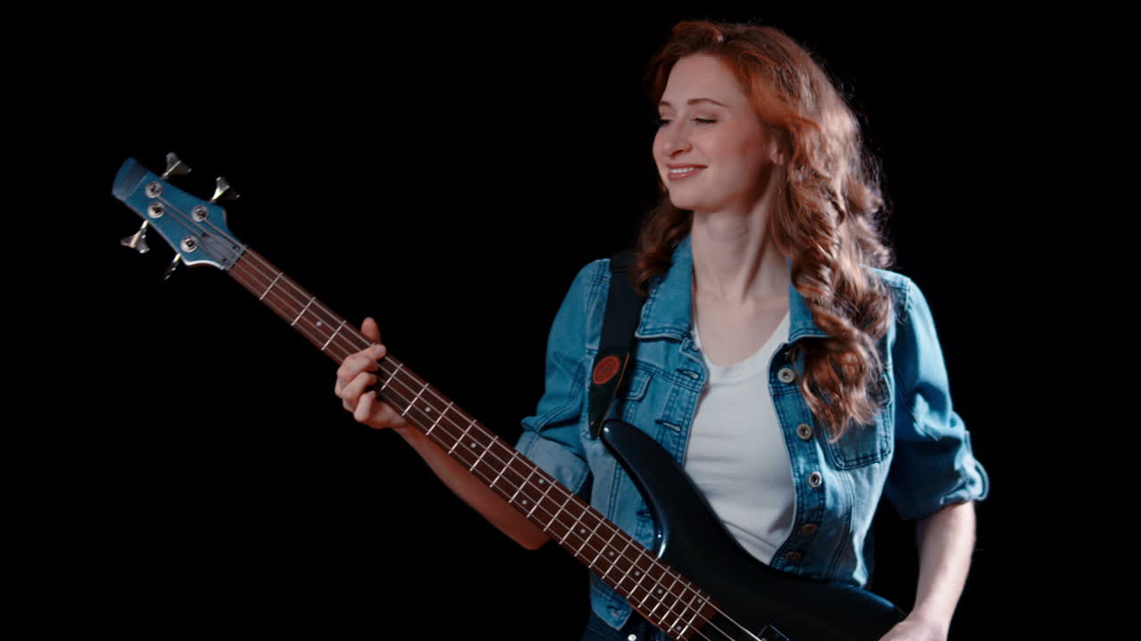 A young caucasian woman plays the bass guitar