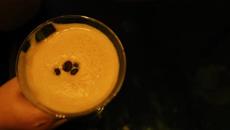 mano sosteniendo un espresso martini en la iluminación oscura