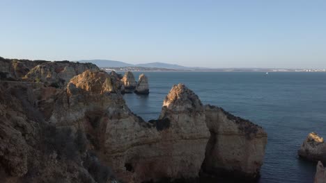 Looking-back-to-Lagos,-Portugal-over-limestone-coastal-rock-formations-at-sunet