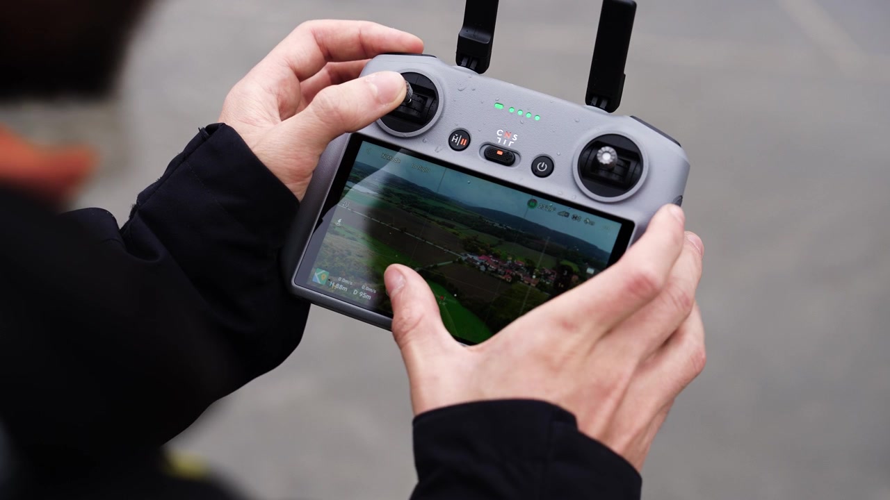 Inquadratura da sopra la spalla di una persona che usa il telecomando del drone e cambia l'angolazione della telecamera