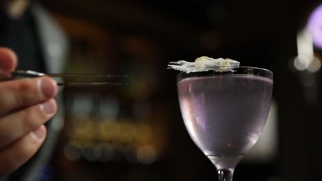 bartender garnishing a purple cocktail