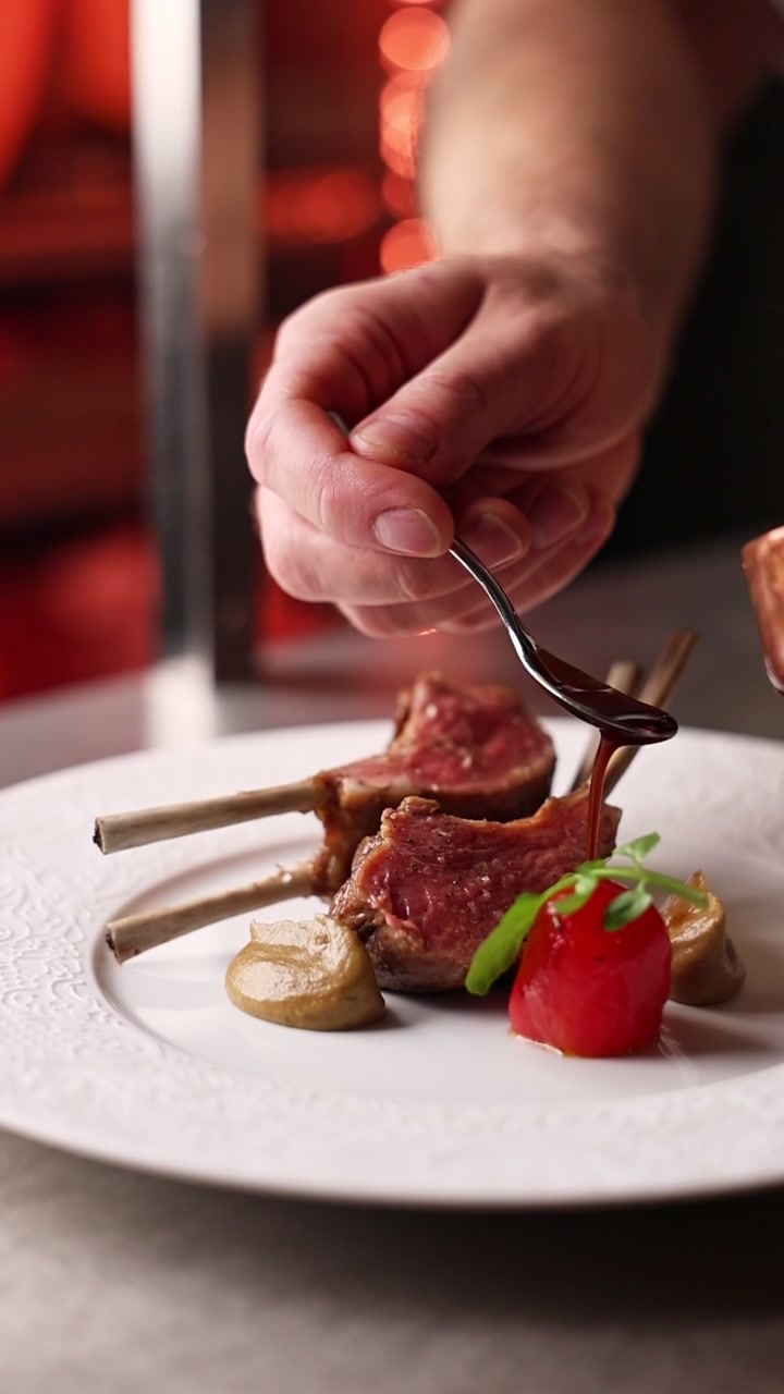 Chef Drizzling Sauce Over Gourmet Lamb Chops in Restaurant Kitchen