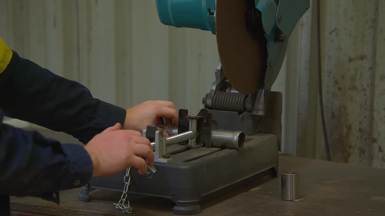 primer plano de trabajador apretando palo de hierro para cortar