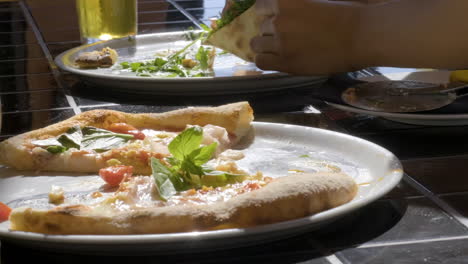 primer plano de una persona irreconocible comiendo pizza en el restaurante