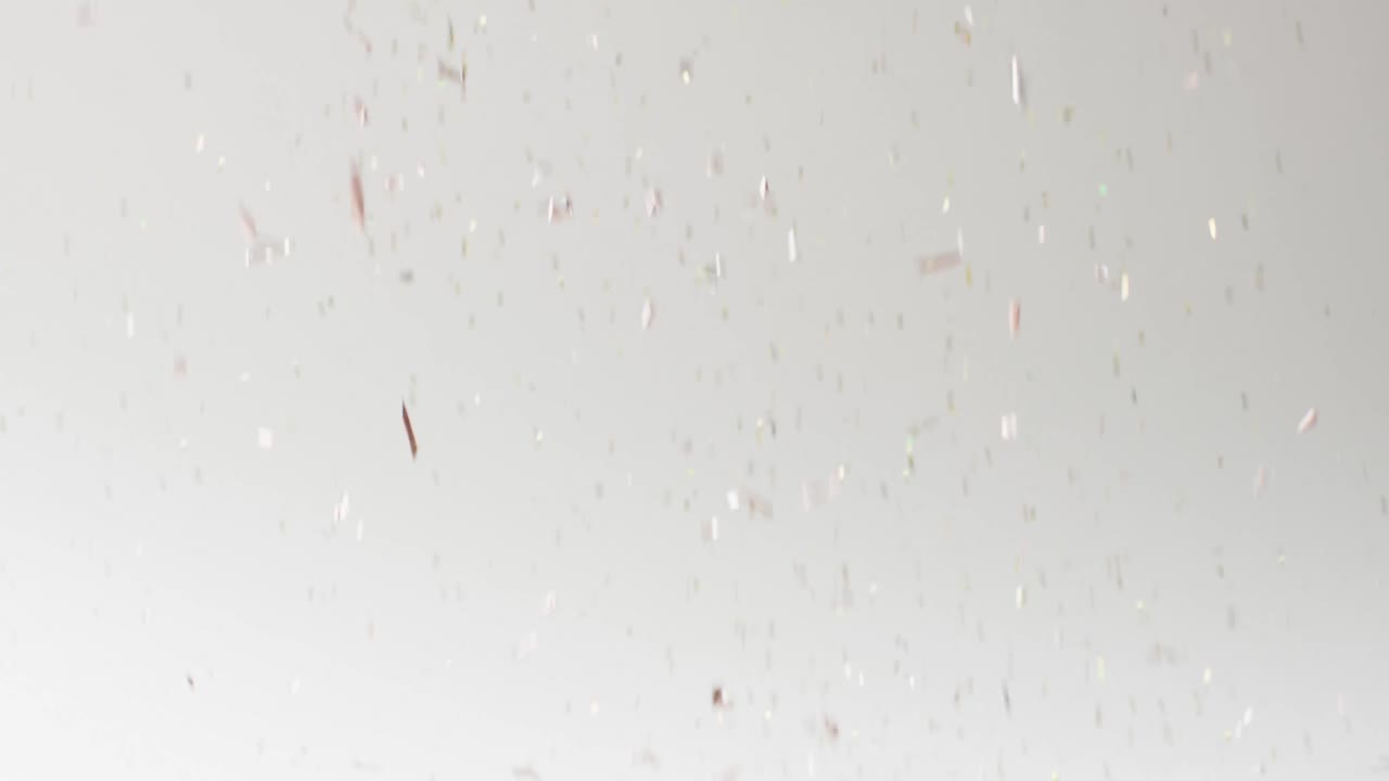 Video of glittering confetti falling on white background