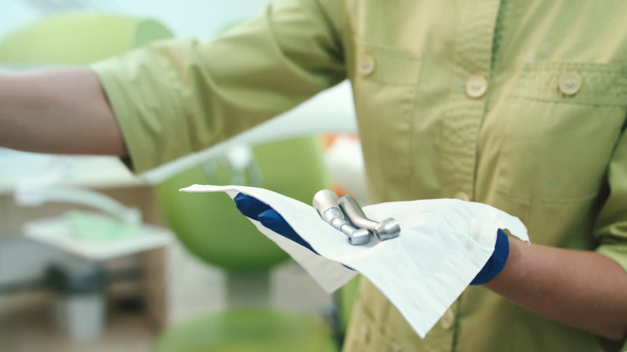 가까이에서 의사의 손이 스테인리스 치과 장비를 청소하고 있습니다.