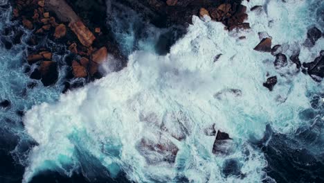 Drone-Asciende-De-Las-Olas-Rompiendo-En-Las-Rocas-En-El-Océano,-Coogee-Beach