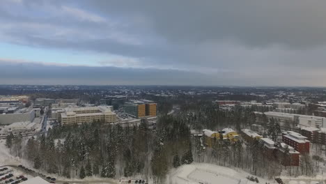 Una-Toma-Aérea-De-Drones-Que-Retrocede-Lentamente-Para-Revelar-Vistas-De-Una-Ciudad-Urbana-Densamente-Poblada-Cubierta-De-Nieve-Blanca-Y-Brillante-Durante-El-Invierno