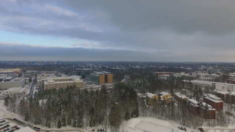 an aerial drone shot that slowly pulls back to reveal views of a densely populated urban city covered in sparkling white snow during winter