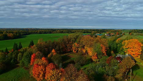 Paisaje-Rural-De-Temporada-De-Otoño,-Casa-Frente-Al-Lago-Rodeada-De-árboles-De-Colores-Vibrantes,-Antena-Hacia-Atrás