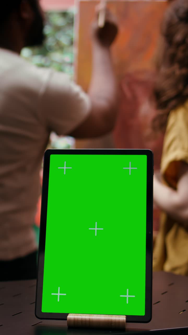 Tablet with Green Screen Display in Art Studio with Artists Painting