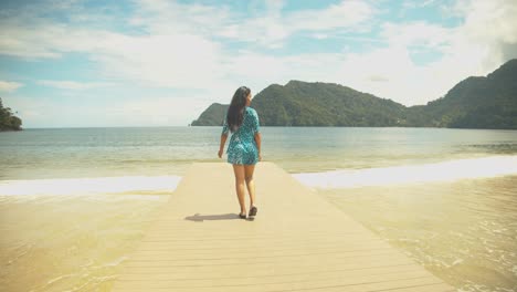 Imágenes-épicas-De-Una-Niña-Caminando-En-Un-Embarcadero-Con-El-Mar-Y-Las-Montañas-De-Fondo