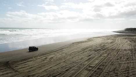 aerial-shot,-4WD-on-the-beach,-track-on-the-car-rotating-angle-in-slow-motion