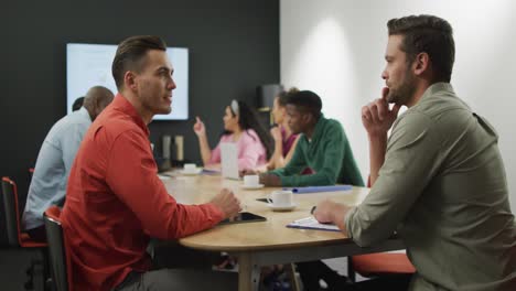 Happy-diverse-business-people-discussing-work-during-meeting-at-office