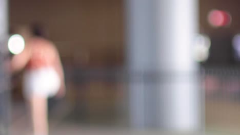 a person in motion near a large column indoors, captured in a blurred sequence.