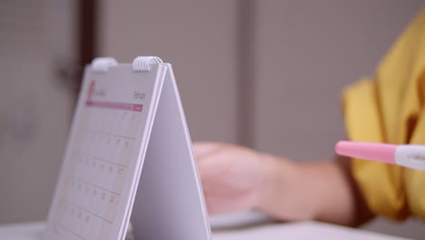 a pregnant woman browsing a calendar to count the days and months of her pregnancy to the date she is due to give birth