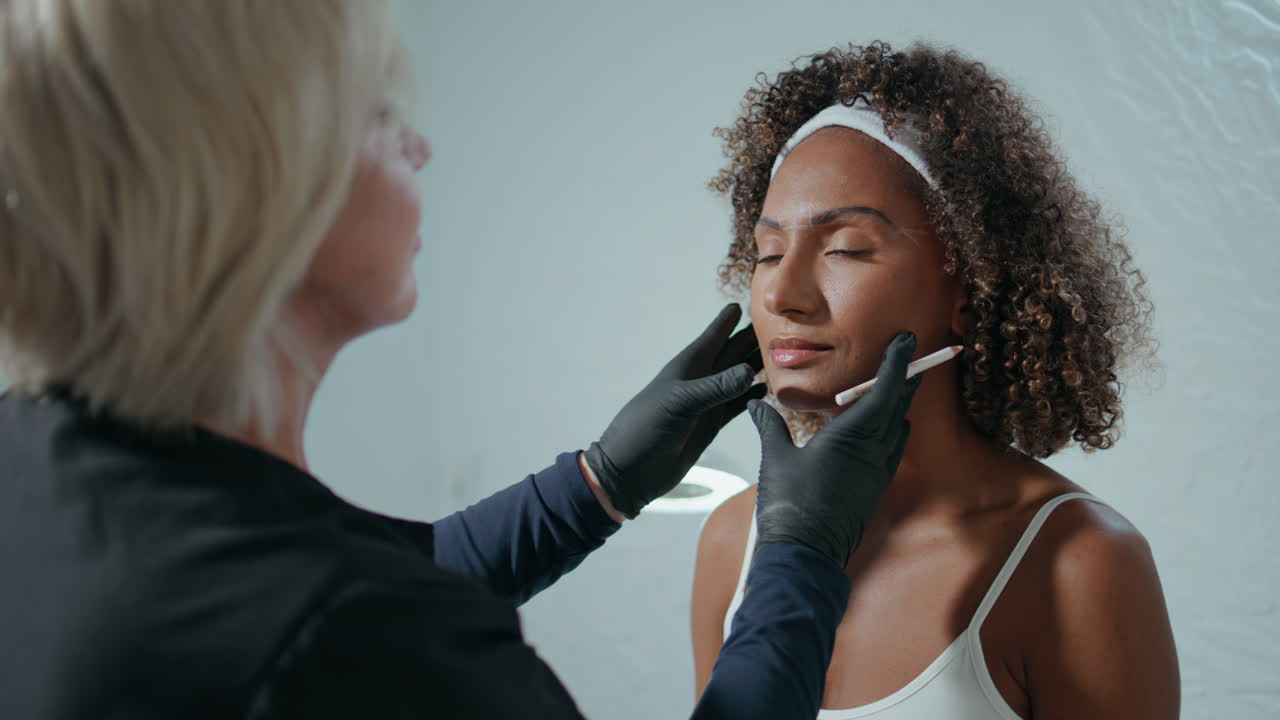 el médico marca el rostro del paciente en un salón de belleza de primer plano.