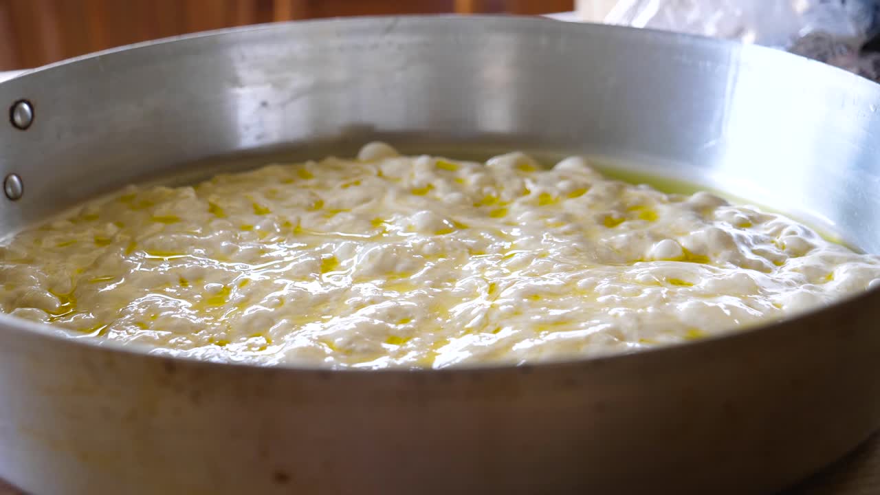 тесто для фокаччи на металлической сковороде перед выпечкой крупным планом - приготовление