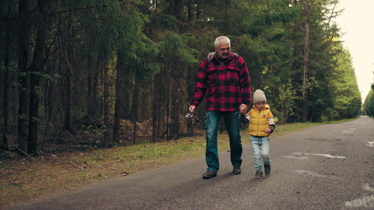 fisherman and his grandson are walking to forest lake strolling on old road in across pinery