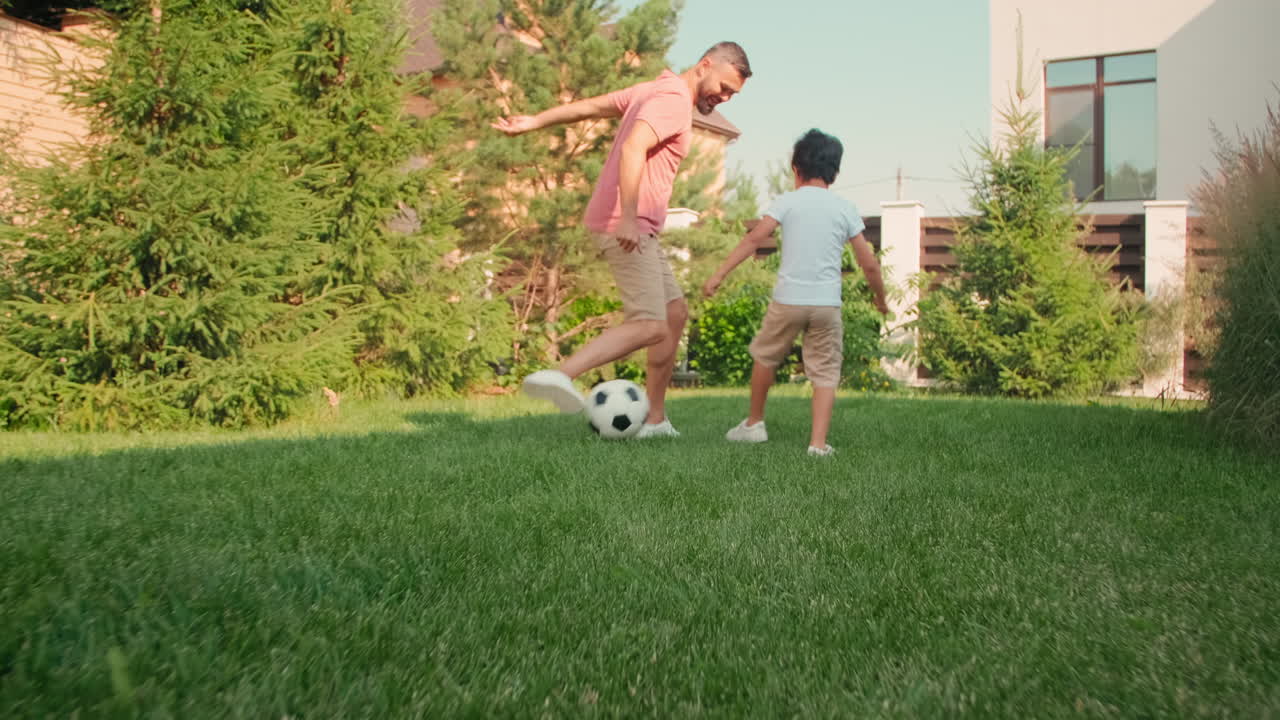 Dad And Son Playing Football In Backyard