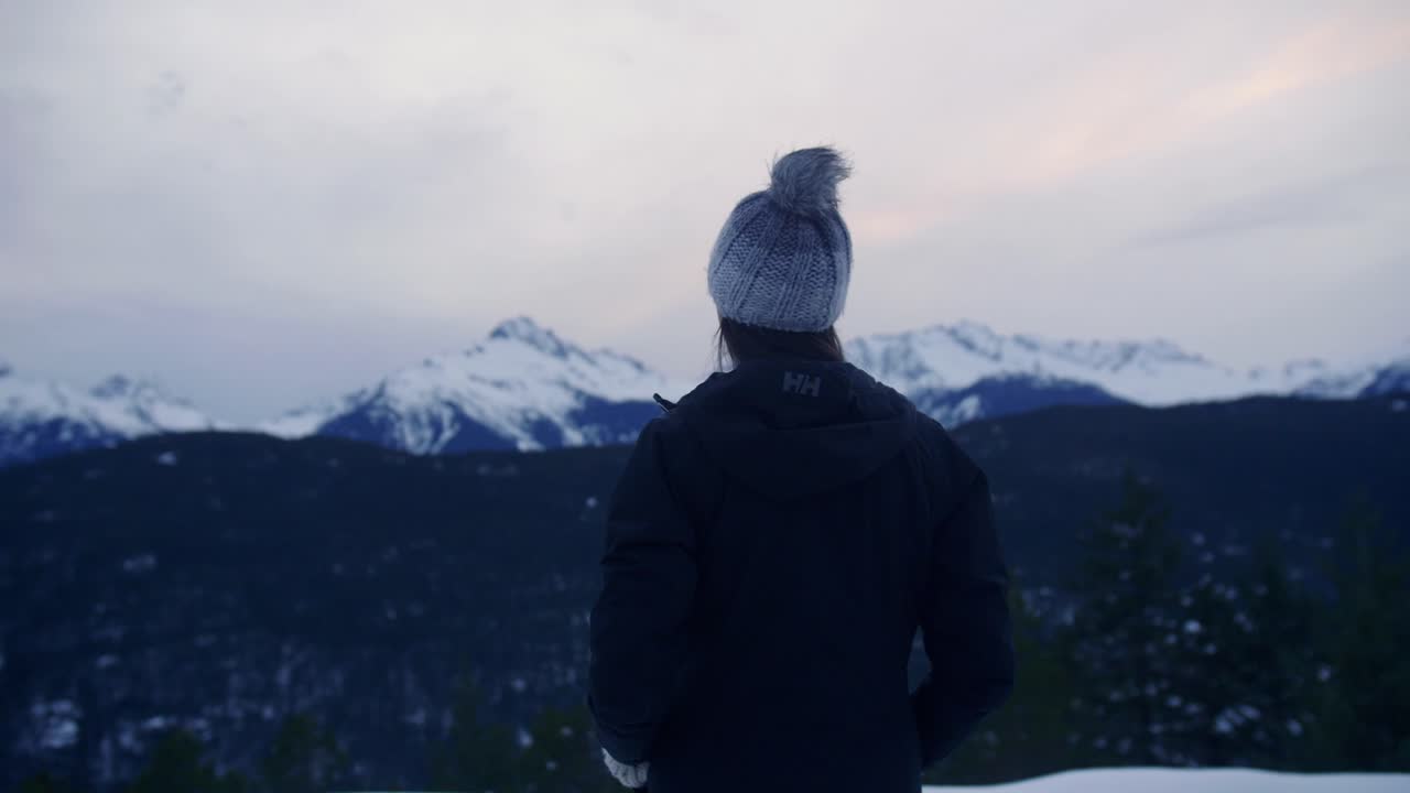 mujer joven al acecho mirando la cordillera nevada