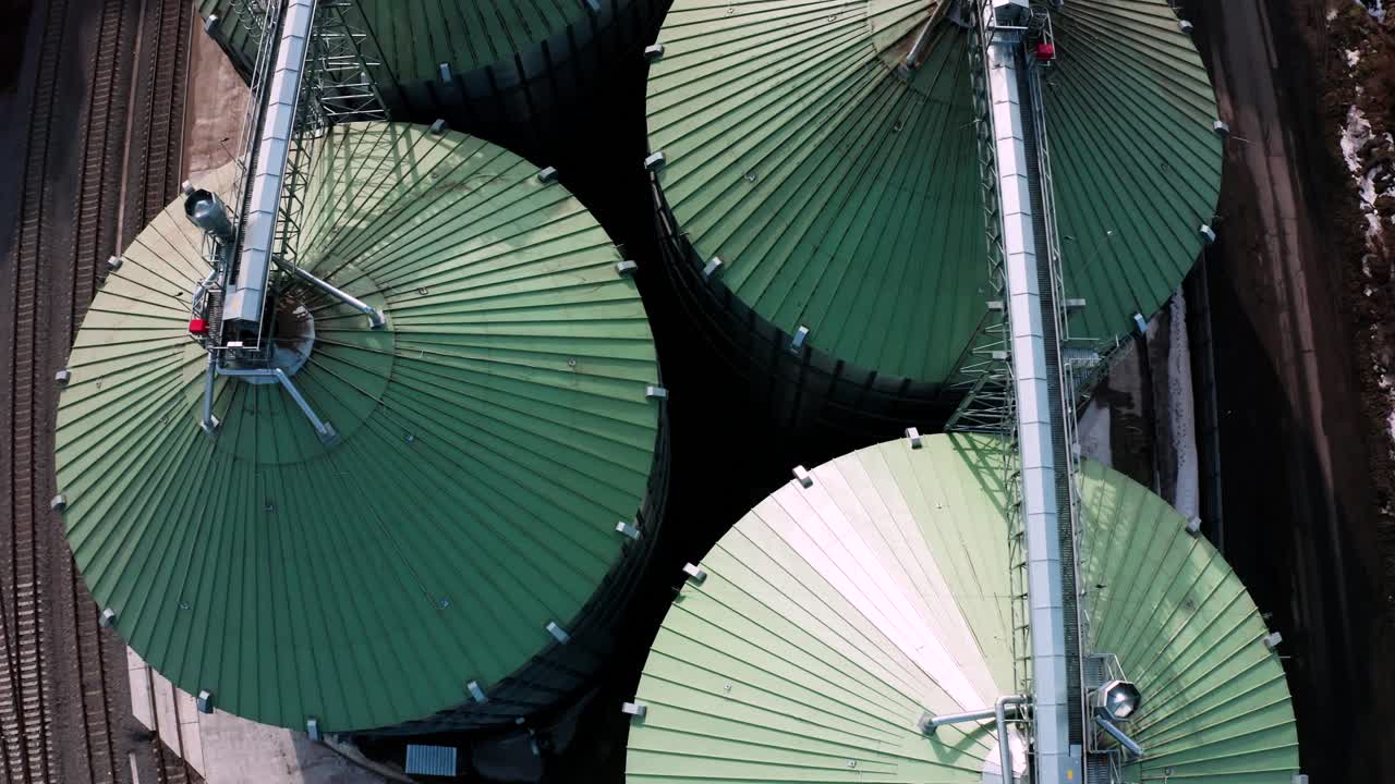 위에서 볼 수 있는 금속 실로: 곡물을 저장하고 가공하기 위한 대형 컨테이너, 농장 내의 은색 곡물 엘리베이터, 위에서 보이는 저장 크, 곡물이 있는 실로.