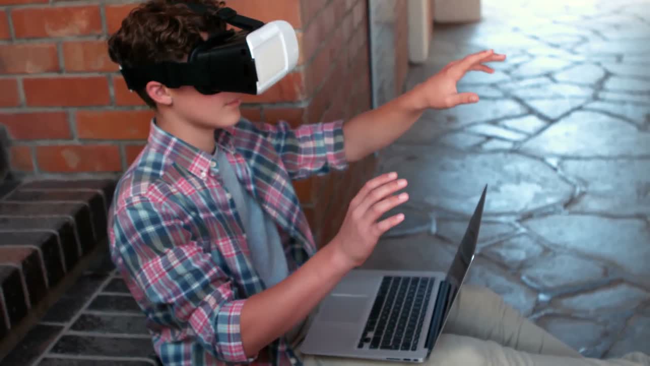 escolar que usa auriculares de vitalidad mientras usa una computadora portátil