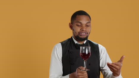 restaurant employee bringing a glass of red wine to clients at the table