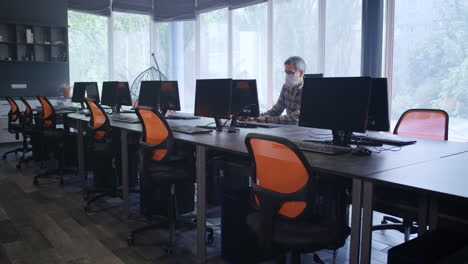 man working in a computer lab wearing a mask