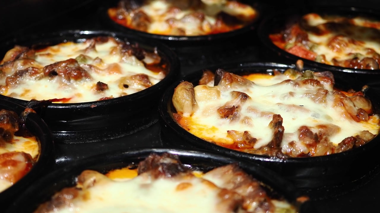 Diverse pietanze calde al forno ricoperte di formaggio fuso.