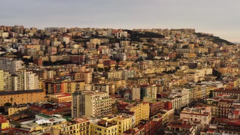 disparo ancho del avión no tripulado que muestra la maravillosa ciudad de nápoles durante la hora dorada iluminación por el sol situado en la colina