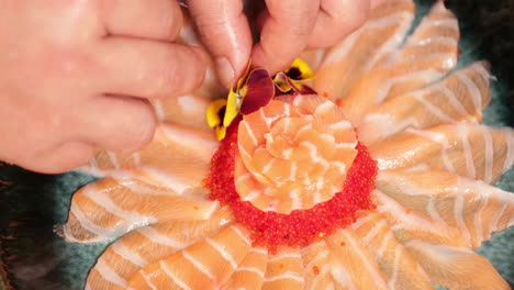 enchapado de comida: chef poniendo flores frescas encima de una rosa de salmón sashimi