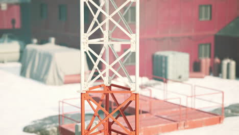 un primer plano de una torre de radio roja y blanca en una zona rural nevada