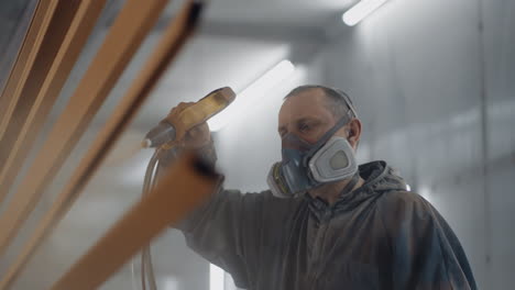 man painting metal in factory