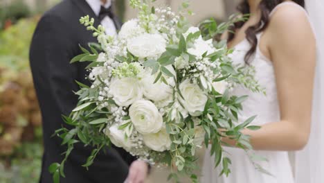 bride holding beautiful white flower bouquet while standing with groom