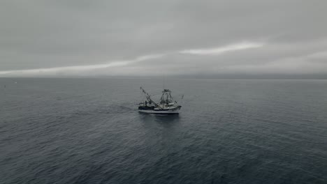 fishing boat sailing at sea on a cloudy morning - wide shot