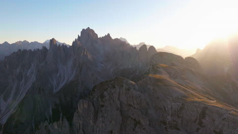 Tre-Cime-sunlit-mountain-terrain-flying-forward-aerial-view-over-gorgeous-South-Tyrol-sunrise-summit