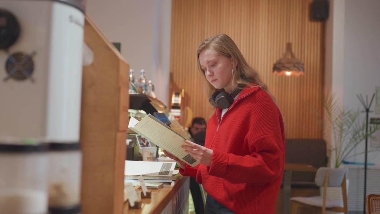 Ung kvinde ser på menu på en café