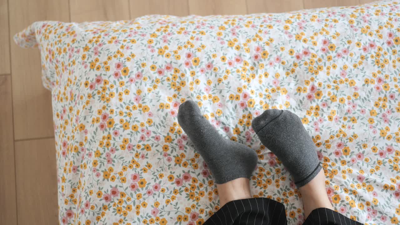 pies de persona en calcetines en una cama con ropa de cama floral