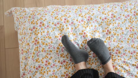 person's feet in socks on a bed with floral bedding