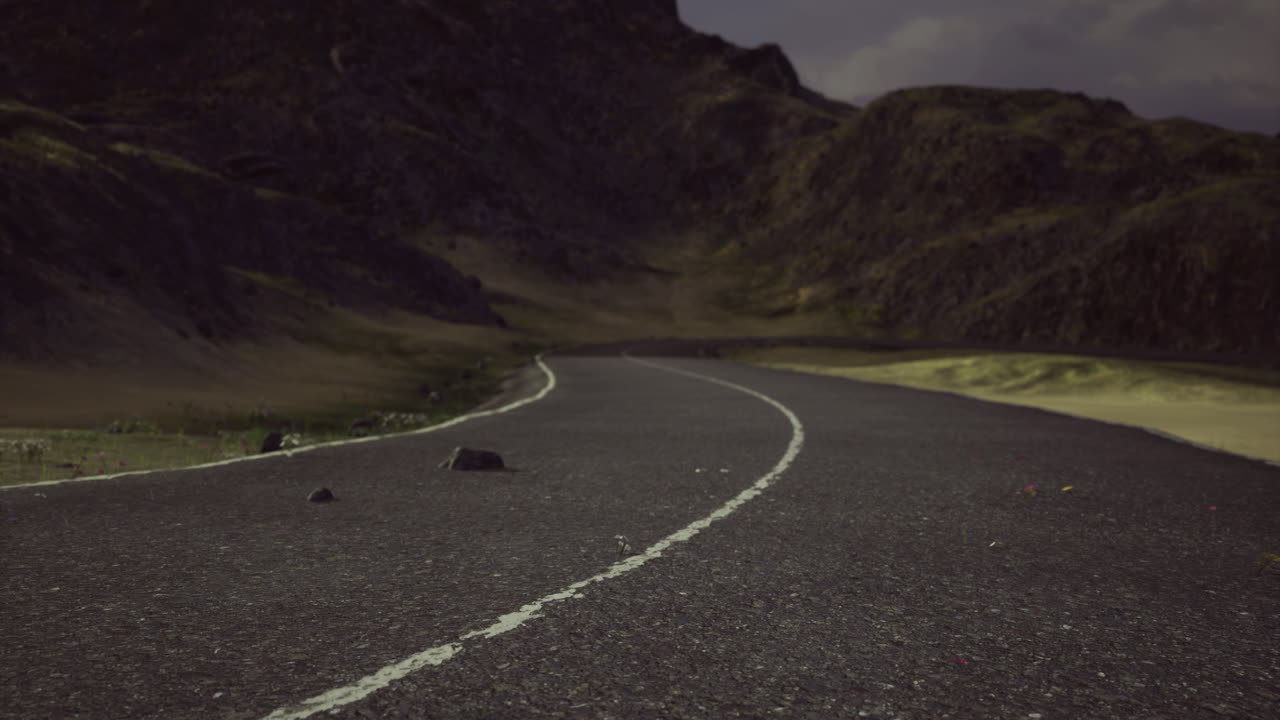 Curving road through mountainous landscape under cloudy sky at dusk