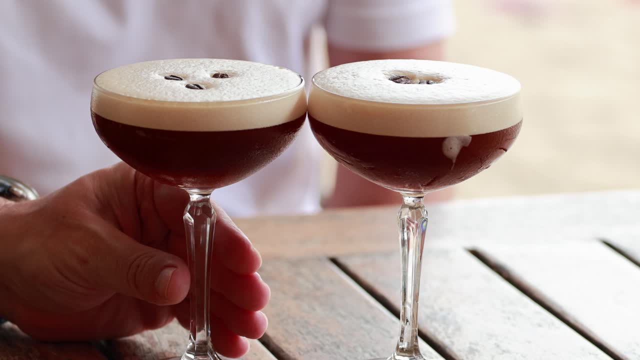 Two cocktails clinked together on a wooden table