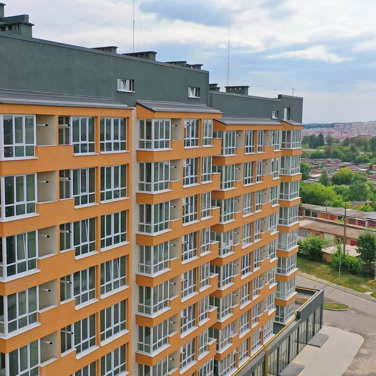 Construction of a modern building in the city. Facade of multistory apartment house with plastic windows in the city. Building of a new architecture concept