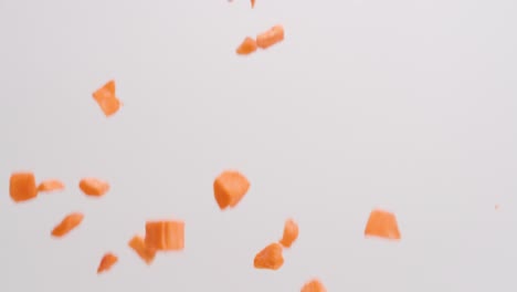 cubed orange sweet potatoes raining down on white backdrop in slow motion