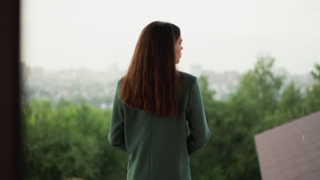 thoughtful woman stands on building roof at rain. businessperson expresses hard burnout trying to calm down on office terrace. depression caused by overwork